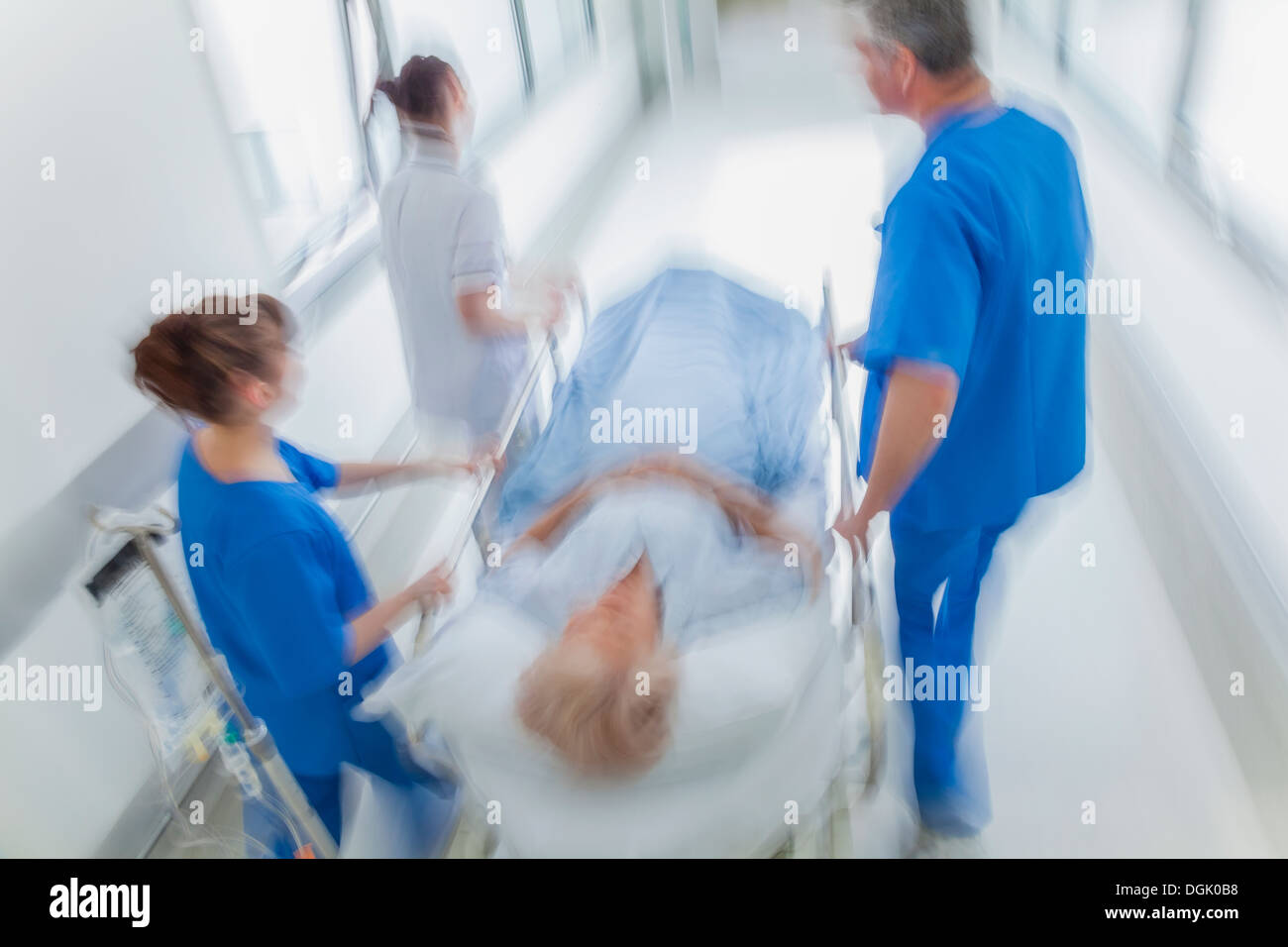 Bewegung verschwommenes Foto einer älteren Patientin auf Keilrahmen oder Gurney mit Geschwindigkeit durch einen Krankenhausflur geschoben Stockfoto