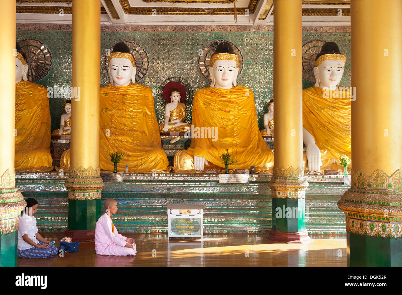 Eine Nonne und Frau beten vor Buddhas in der Shwedagon-Pagode in Yangon, Myanmar. Stockfoto