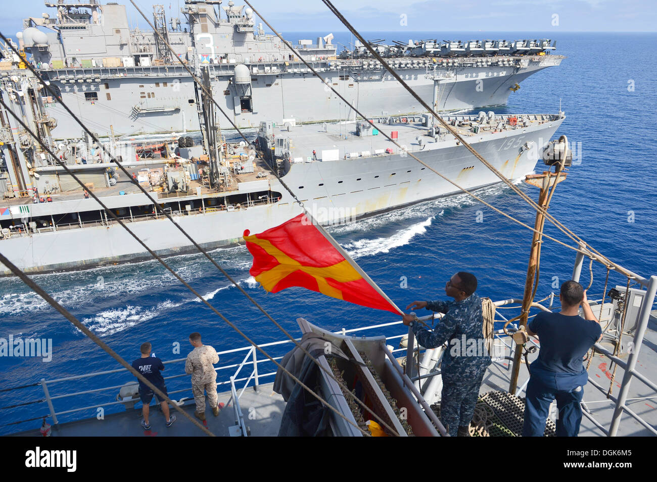 Quartiermeister Seemann Patrick Holmes senkt die Romeo-Flagge an Bord der amphibischen Dock Landungsschiff USS Carter Hall (LSD 50) während ein Nachschub auf dem Meer mit den Military Sealift Command Flotte Nachschub Öler USNS Leroy Grumman (T-AO-195). Carter Hall Stockfoto