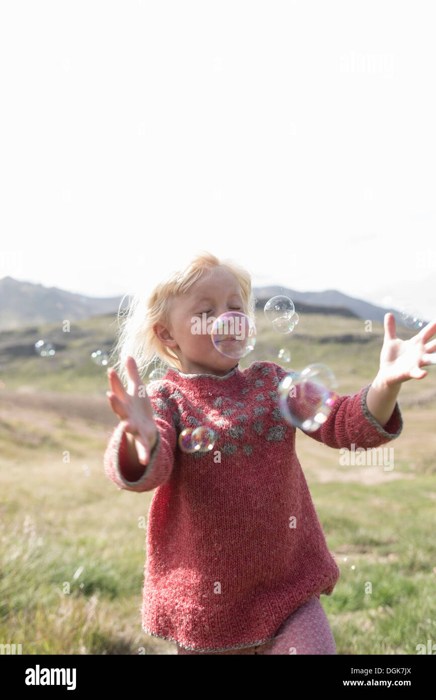 Junges Mädchen mit Augen geschlossen ausgeführt, um Luftblasen zu fangen Stockfoto