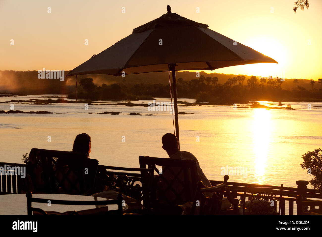 Junges Paar im Sonnenuntergang über den Zambesi River in der Nähe von Viktoriafälle, Hotel Royal Livingstone, Sambia Afrika Urlaub Stockfoto