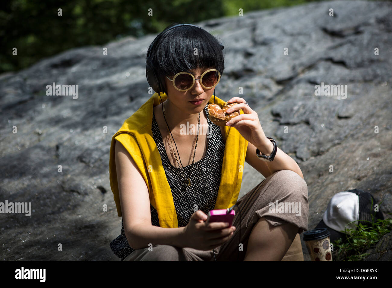 Junge Frau Essen Snack mit MP3-player Stockfoto