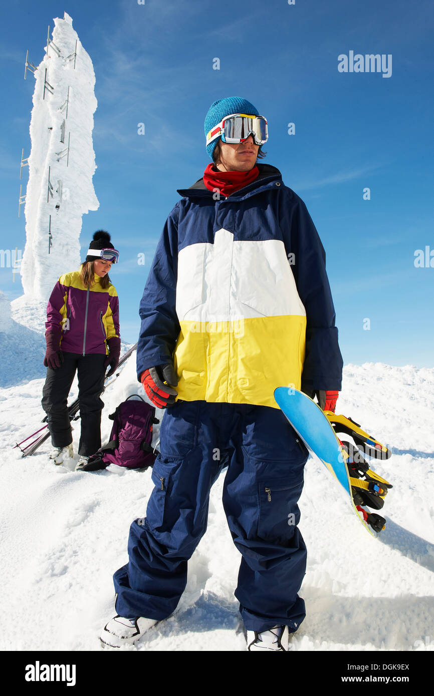 Snowboarder und Skifahrer an der Spitze des Berges mit Ausrüstung vor Eisskulptur Stockfoto