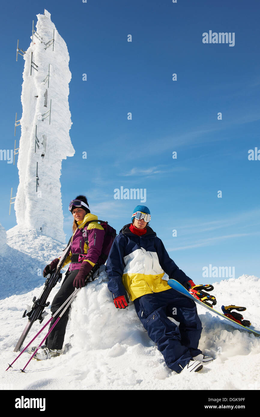 Snowboarder und Skifahrer an der Spitze des Berges mit Ausrüstung vor Eisskulptur Stockfoto