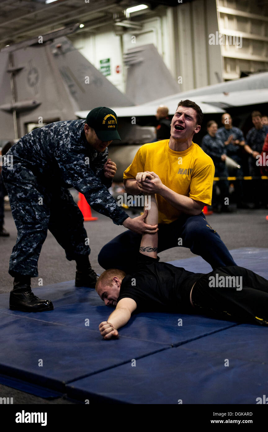 Ein US-Seemann, oben rechts, wehrt einen simulierten Angriff während einer Oleoresin Capsicum Spray Qualifikation an Bord des Flugzeugträgers USS George Washington (CVN-73) 16. Oktober 2013, in das Ostchinesische Meer. Das Schiff und die eingeschifften Carrier Air Wing (CVW) 5 pr Stockfoto
