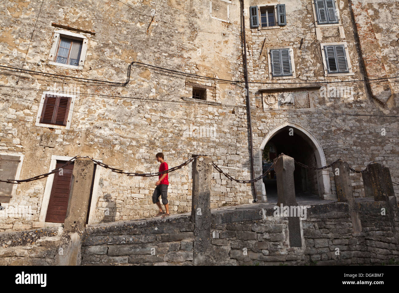 Ein Junge in einem roten Hemd außerhalb der historischen mittelalterlichen Mauern in Motovun. Stockfoto