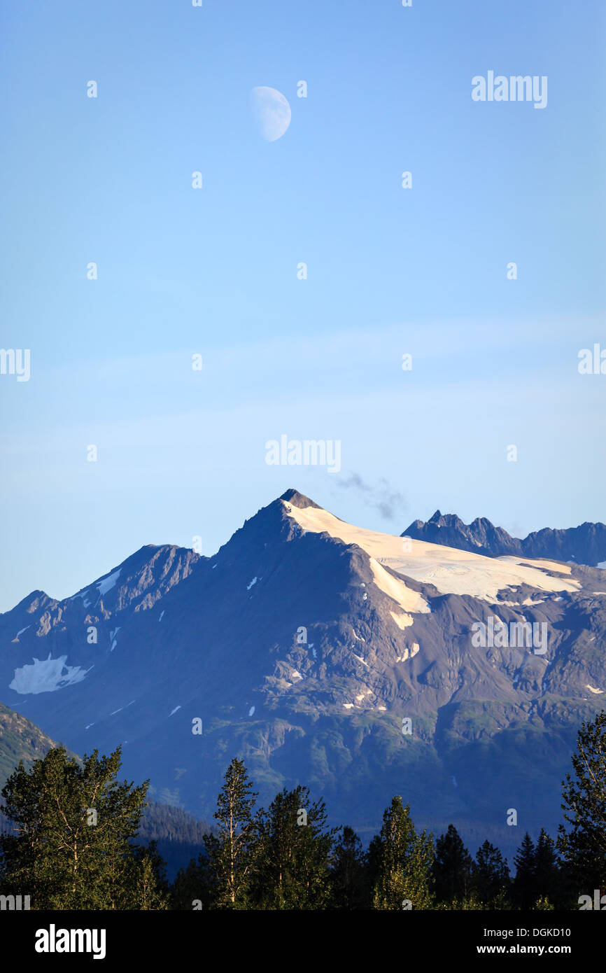 Der Halbmond offenbart sich am Sommerabend über den Berggipfeln Alaskas Stockfoto