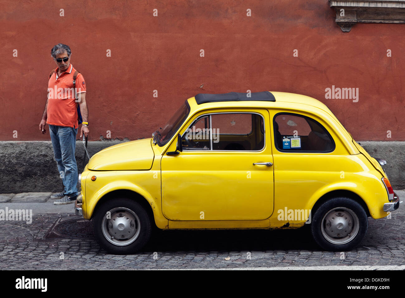Ein Mann nimmt scheinbar eine Vintage Fiat 500 für einen Spaziergang in Bologna. Stockfoto