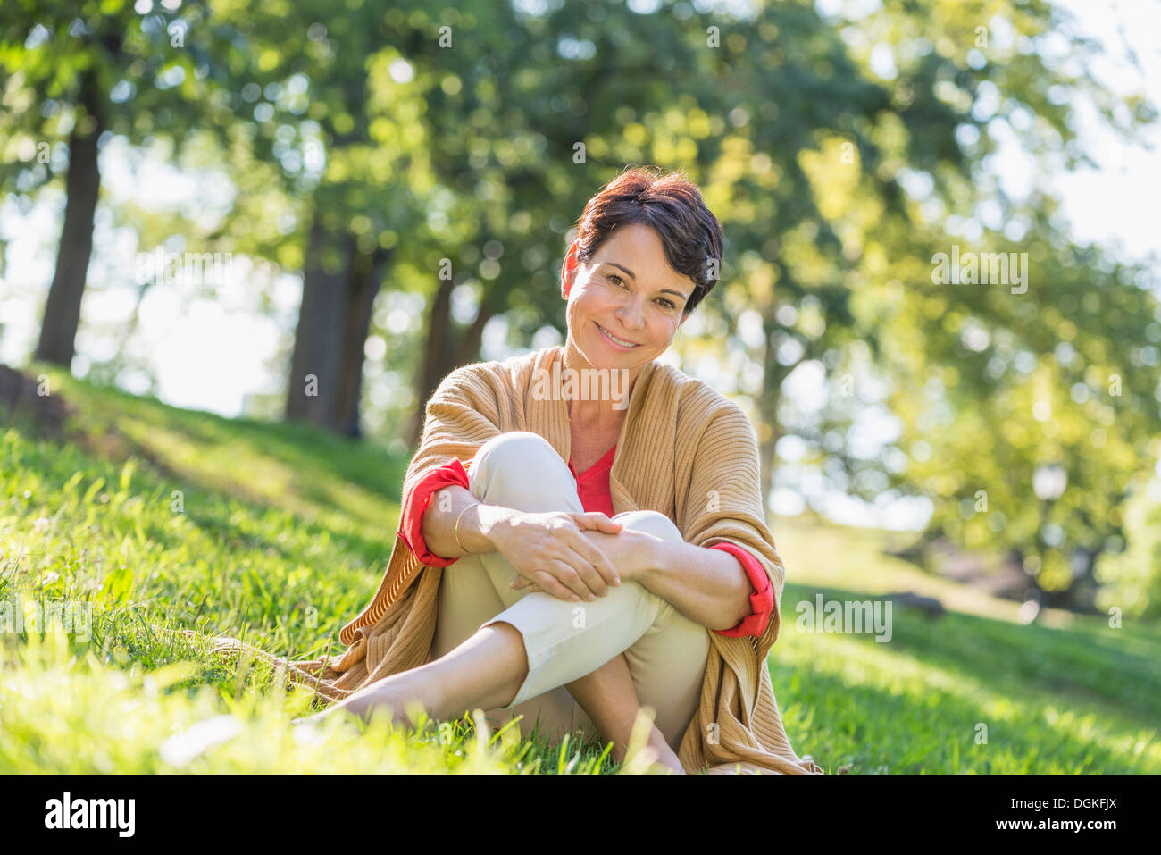 Reife Frau sitzen auf dem Rasen im park Stockfoto