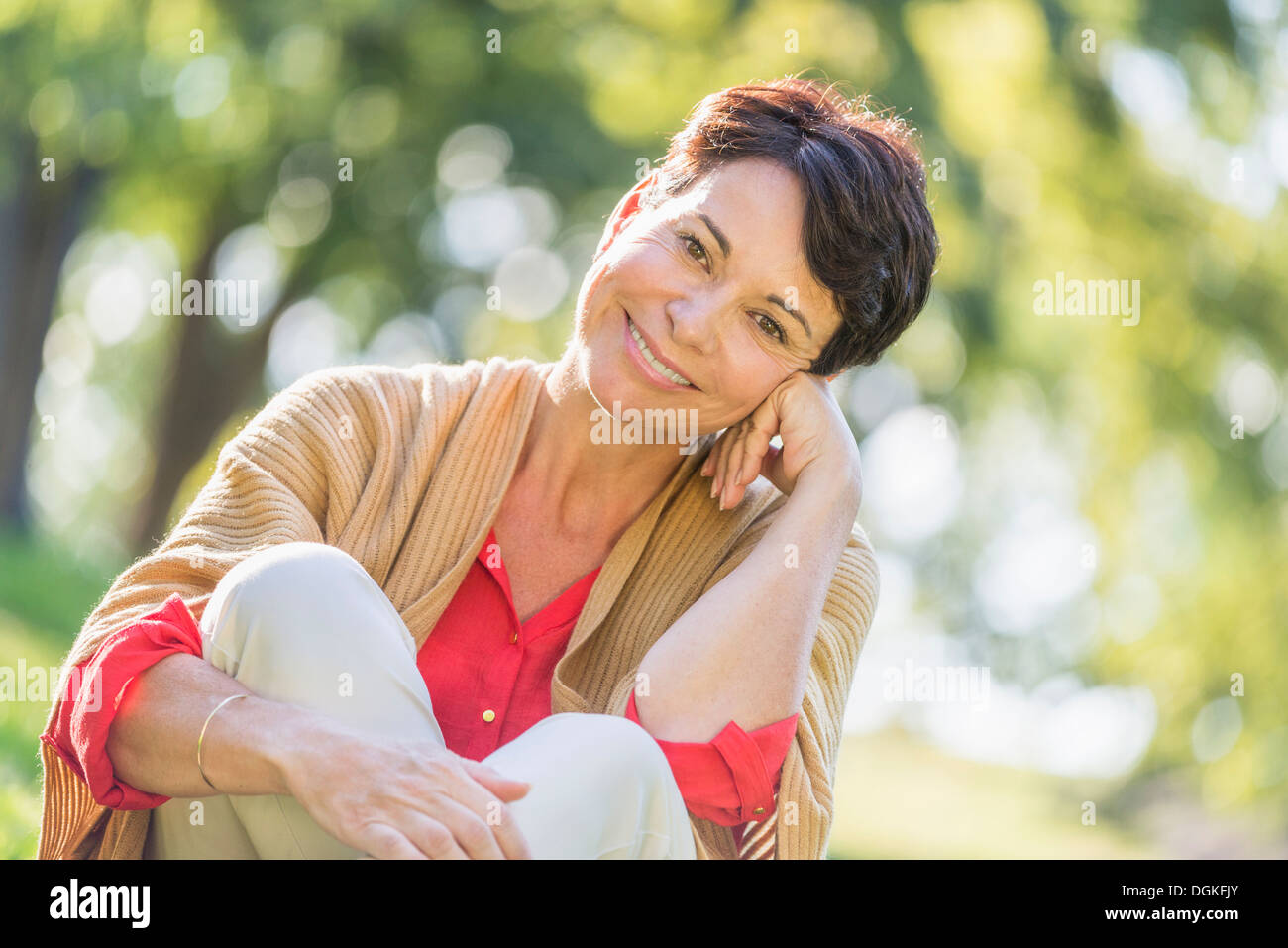 Reife Frau sitzen auf dem Rasen im park Stockfoto