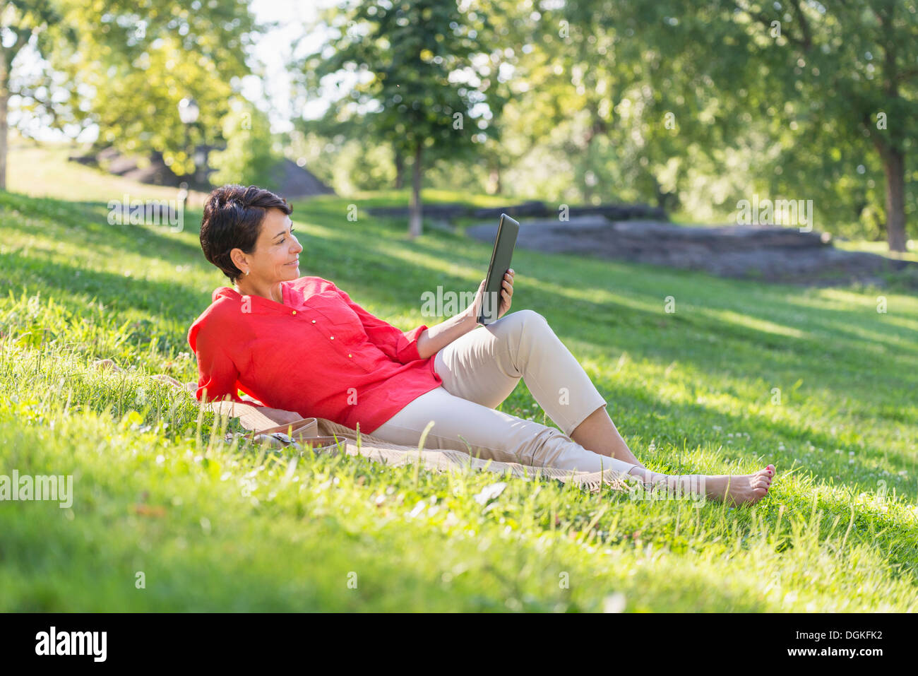 Reife Frau auf dem Rasen liegen und mit digital-Tablette Stockfoto