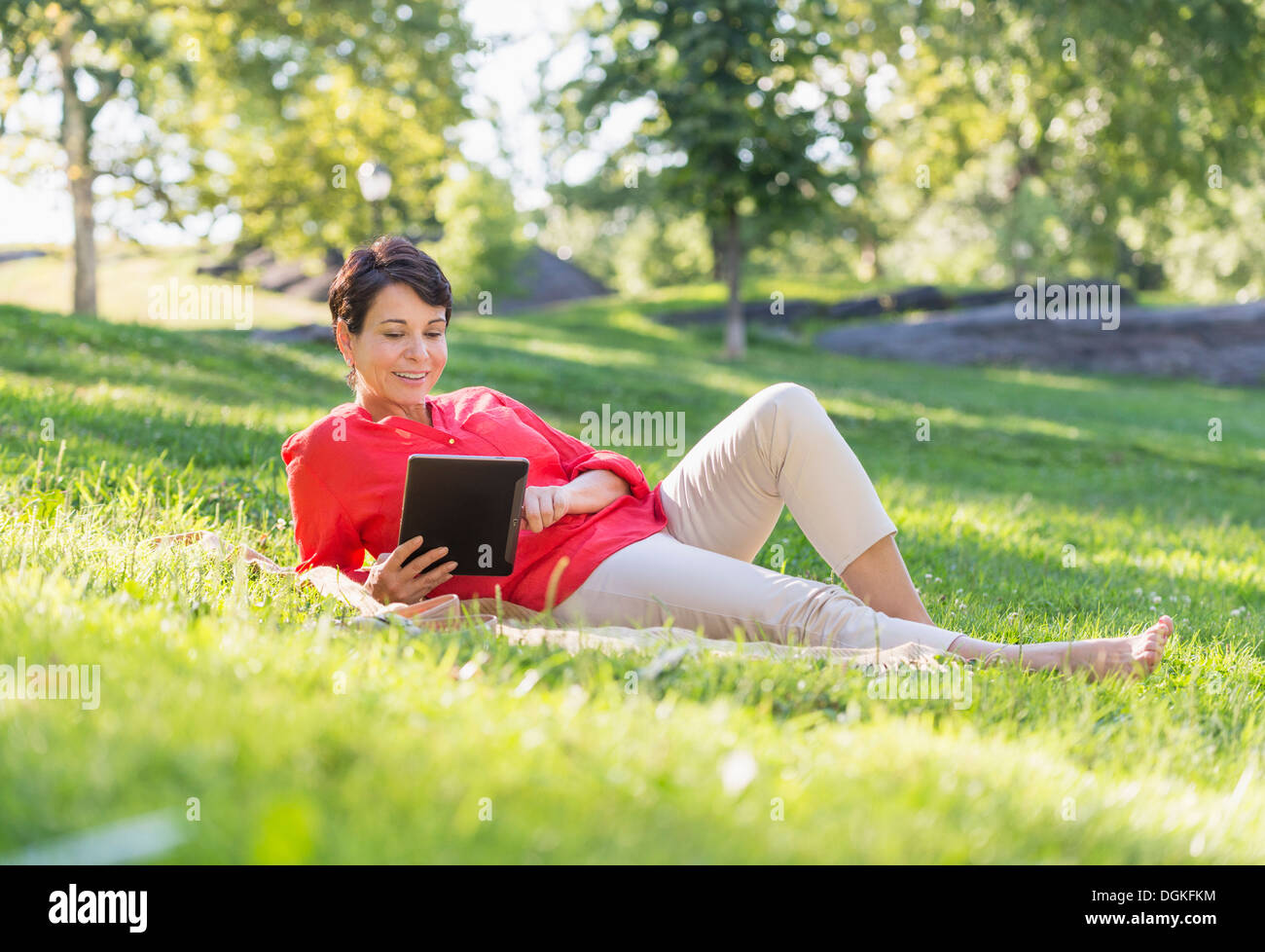 Reife Frau auf dem Rasen liegen und mit digital-Tablette Stockfoto