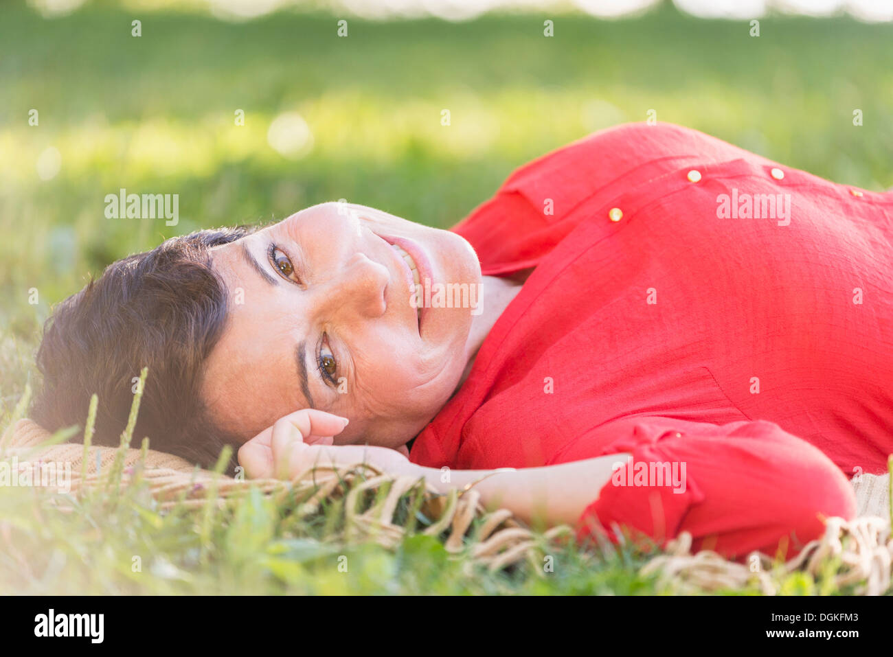 Reife Frau liegend auf dem Rasen Stockfoto