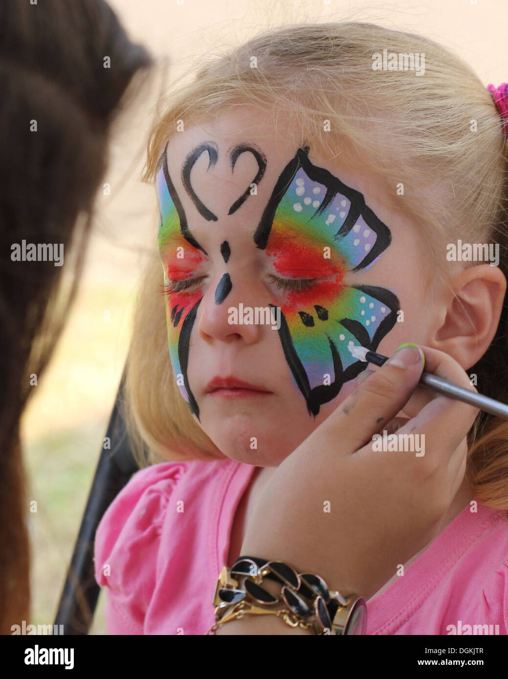 blonde Mädchen, das ihr Gesicht gemalt mit einem Schmetterling Stockfoto