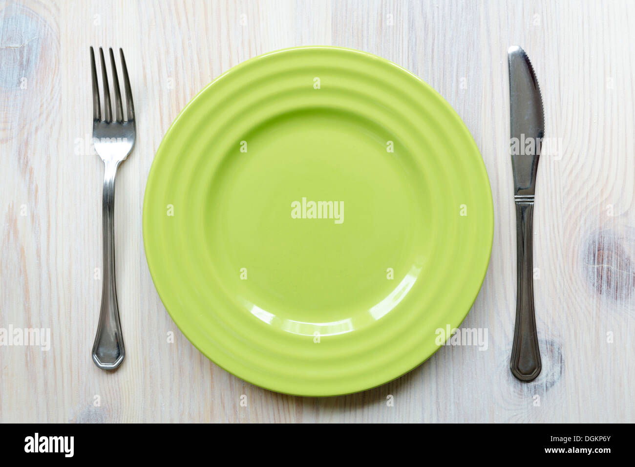 leere Teller-Teller grün auf dem Vintage Holztisch mit Messer und Gabel Stockfoto