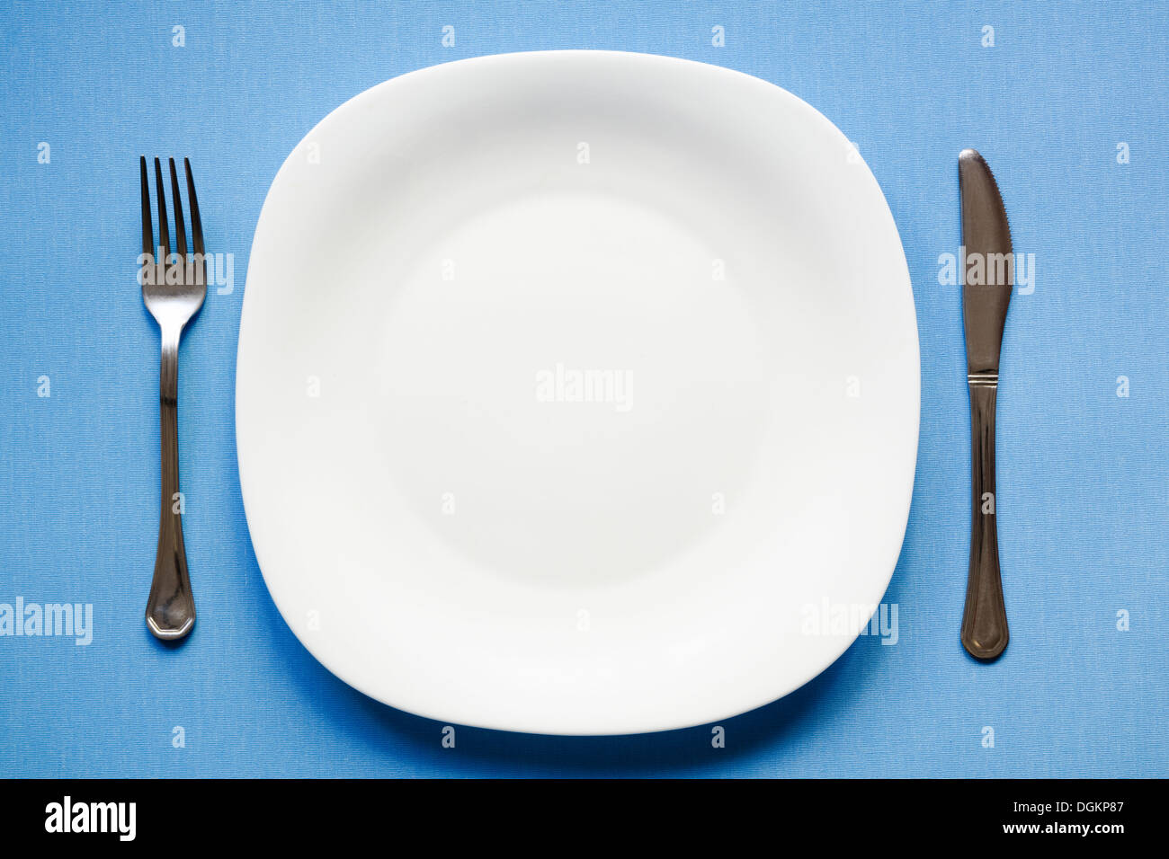 weiße leere Schale auf die Blaue Tischdecke mit Messer und Gabel Stockfoto