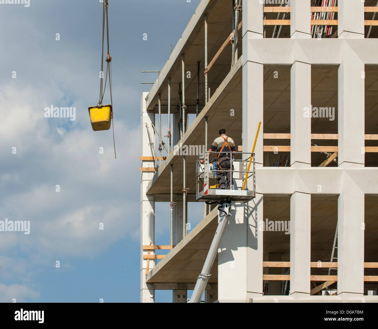 Arbeitnehmer in einem Lift auf einer Baustelle, ein konkretes Schiff wird von einem Kran, Arbeitssicherheit, PublicGround gesenkt Stockfoto