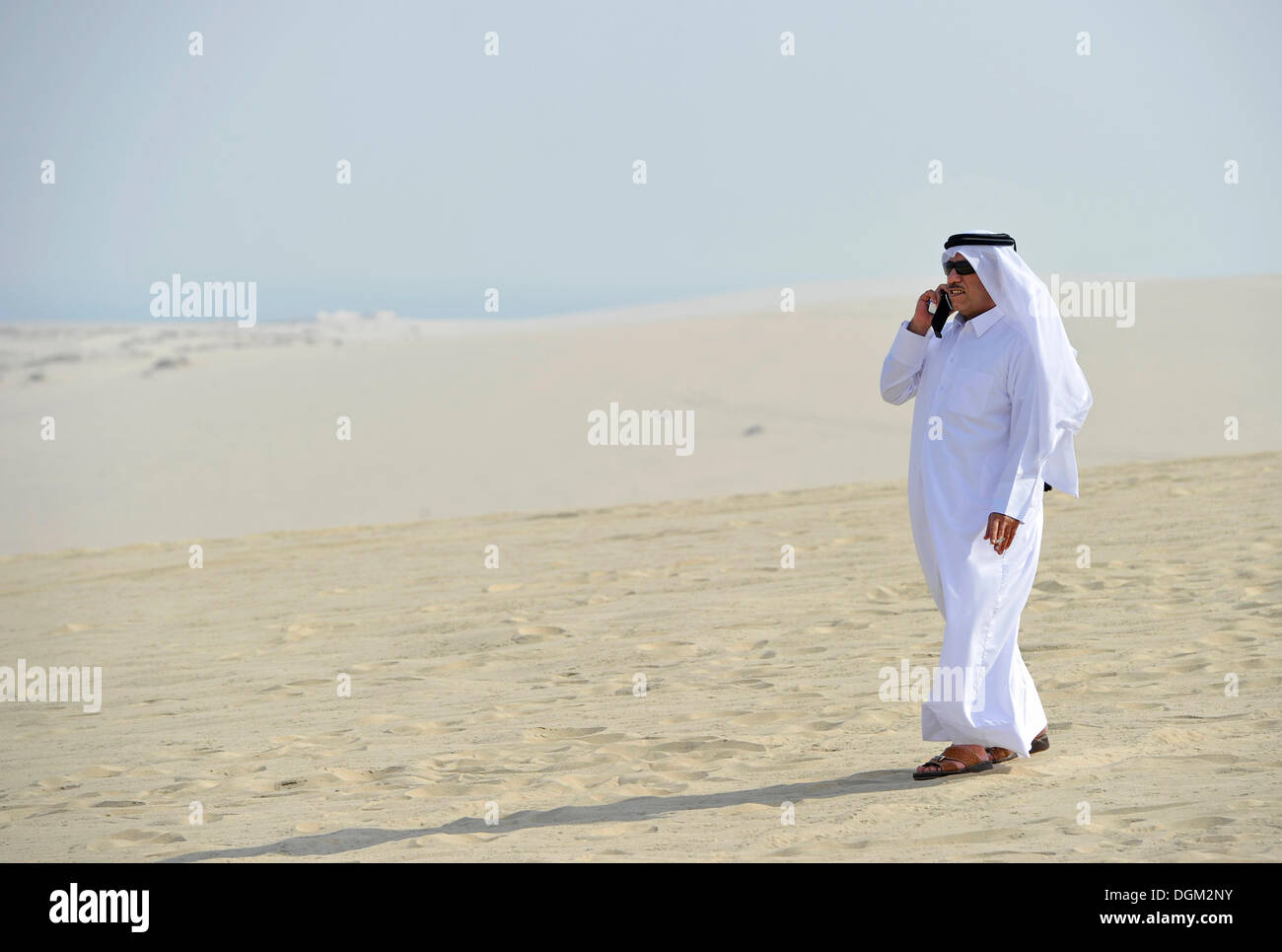 Katar auf einem Handy in der traditionellen Kleidung mit Gutra, Emirat Katar, Persischer Golf, mittleren Osten, Asien Stockfoto
