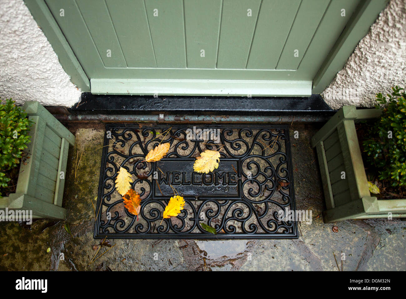 Buntes Herbstlaub, die auf eine willkommene Matte vor einer Hütte Tür mit den Worten willkommen auf die Matte gefallen haben Stockfoto