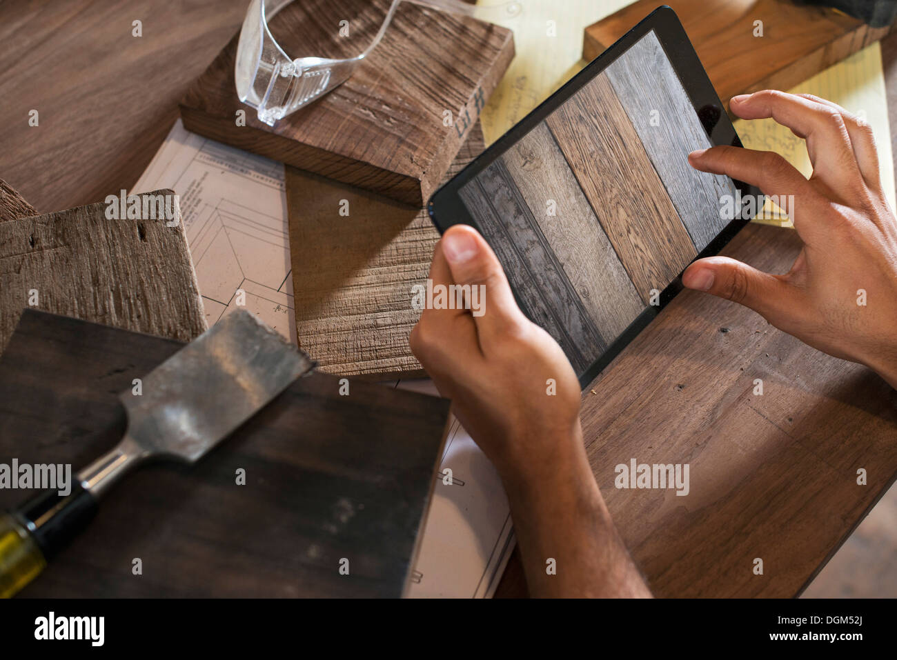 Ein junger Mann in einer Werkstatt. Verwenden eine digitale-Tablette, Aufzeichnungen und Foto-Objekte. Stockfoto