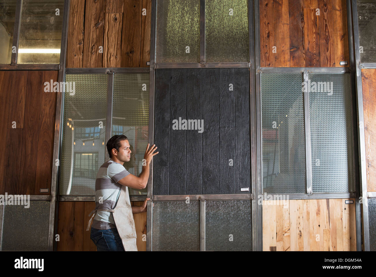 Ein junger Mann in einer Werkstatt. Verwenden eine digitale-Tablette, Aufzeichnungen und Foto-Objekte. Stockfoto