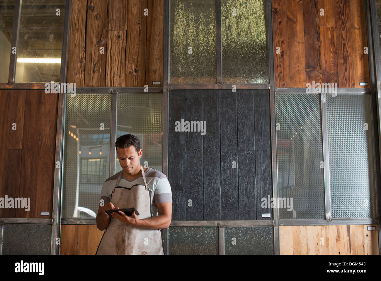 Ein junger Mann in einer Werkstatt. Verwenden eine digitale-Tablette, Aufzeichnungen und Foto-Objekte. Stockfoto