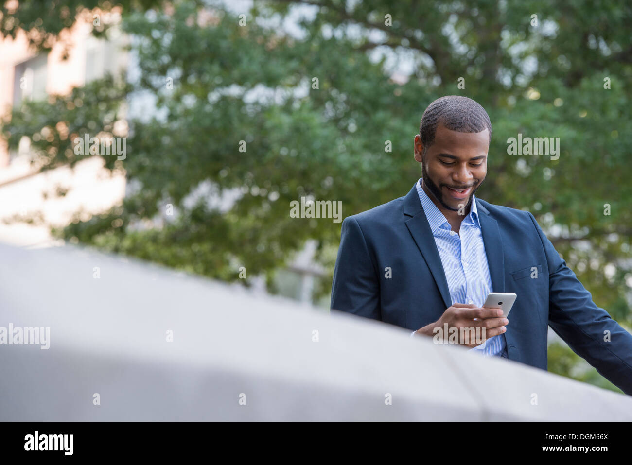 Sommer. Ein Mann in eine blaue Jacke und offenes Hemd mit Kragen mit einem Smartphone. Stockfoto