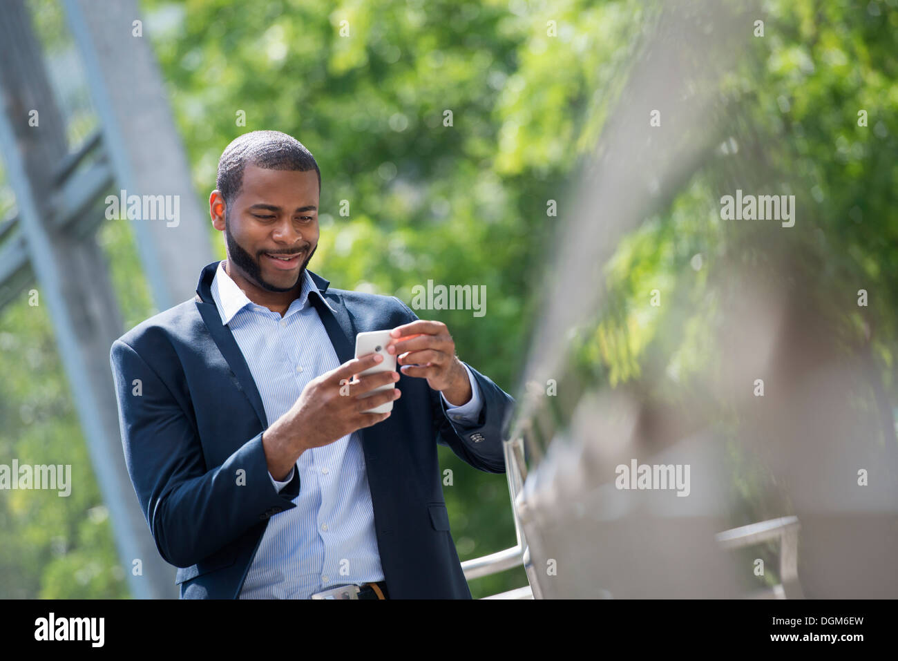 Sommer. Ein Mann in eine blaue Jacke und offenen necked Hemd. Verwenden ein smart Phone. Stockfoto