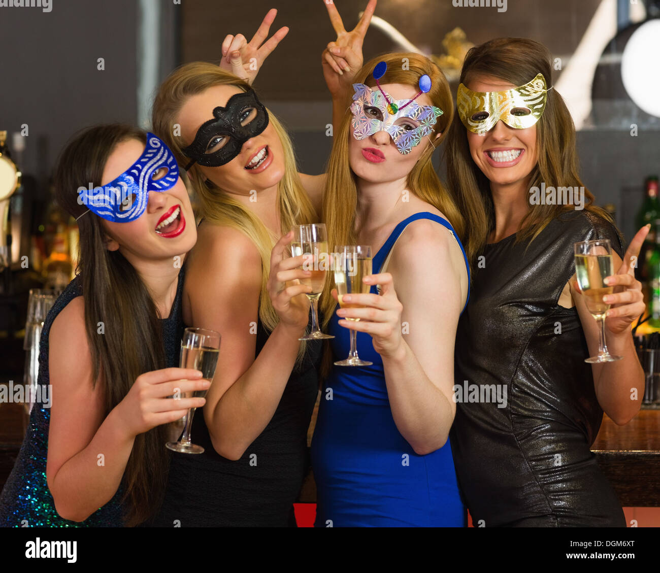 Attraktive Frauen tragen Masken mit Champagner Stockfoto