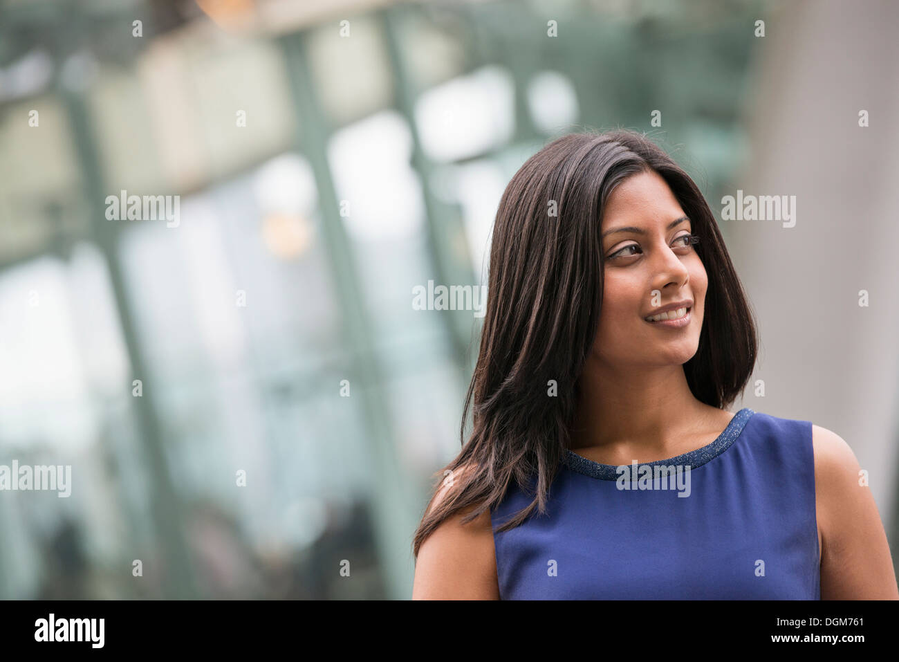 Business-Leute. Eine Frau mit langen schwarzen Haaren, trägt ein blaues Kleid. Stockfoto