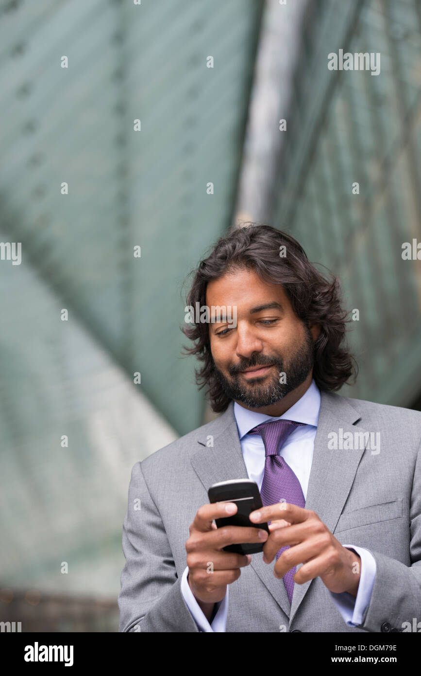 Business-Leute. Ein Mann im Anzug mit einem Vollbart und lockiges Haar. Sein Telefon benutzen. Stockfoto