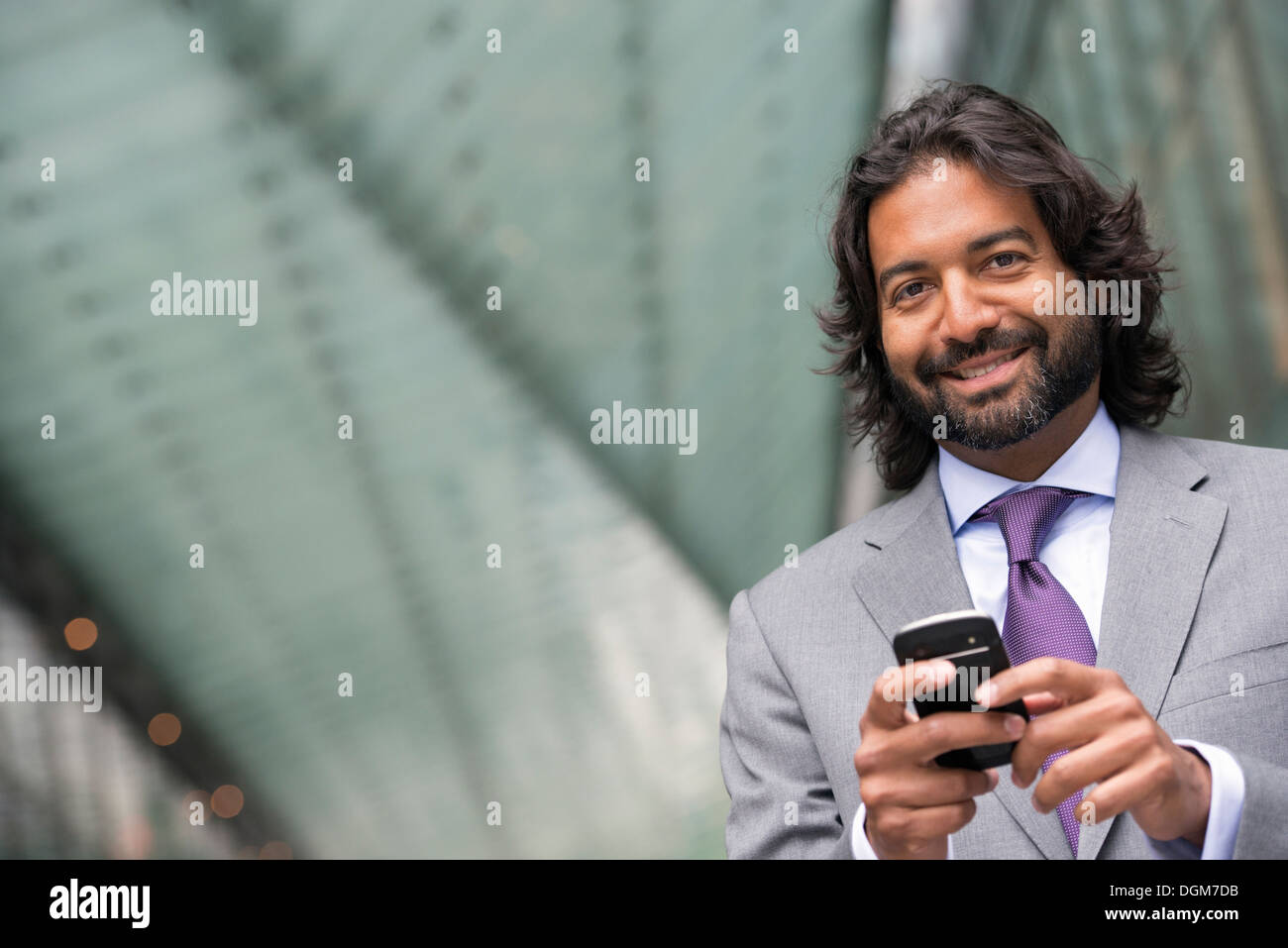 Business-Leute. Ein Mann im Anzug mit einem Vollbart und lockiges Haar. Sein Telefon benutzen. Stockfoto