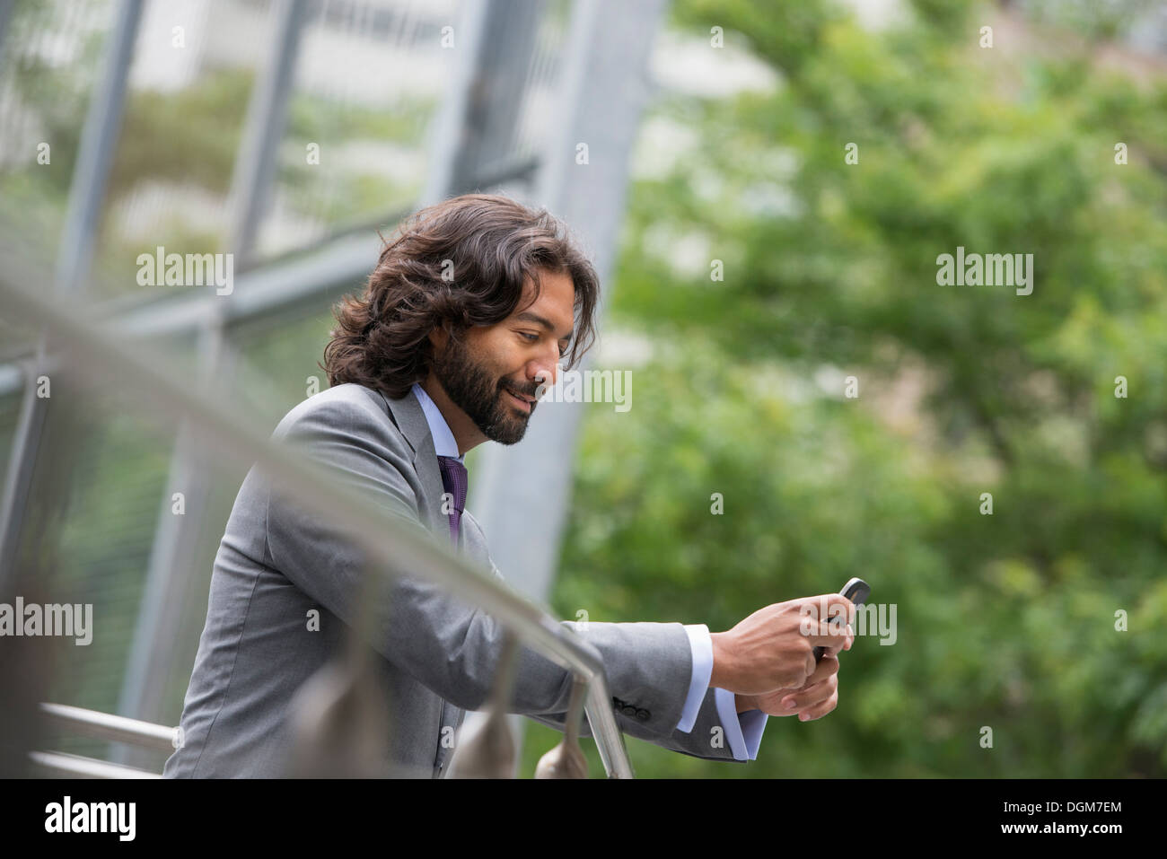 Business-Leute. Ein Mann in einem Anzug mit braunen lockigen Haar und einem Bart. Auf seinem Handy. Stockfoto