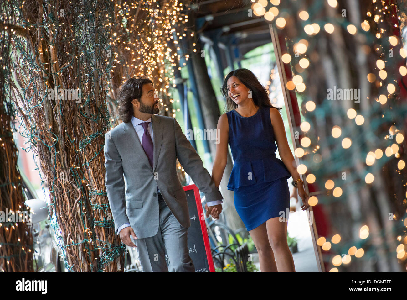 Business-Leute. Zwei Menschen, Mann und Frau Hand in Hand und Fuß unter einer Pergola mit Lichterketten beleuchtet. Stockfoto