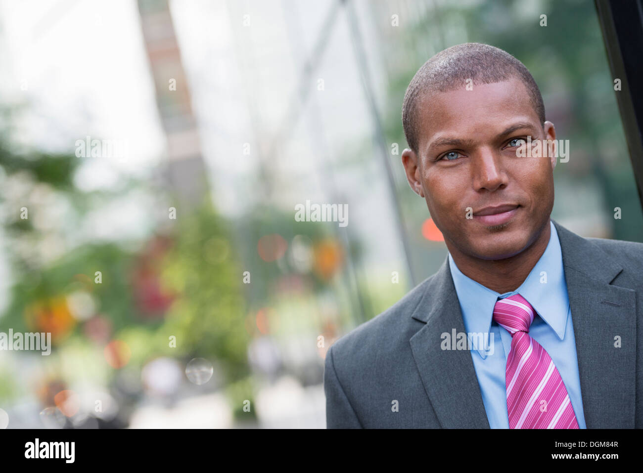 Ein junger Mann in einem Business-Anzug, ein hellblaues Hemd mit roter Krawatte. Auf einer Stadtstraße. Stockfoto