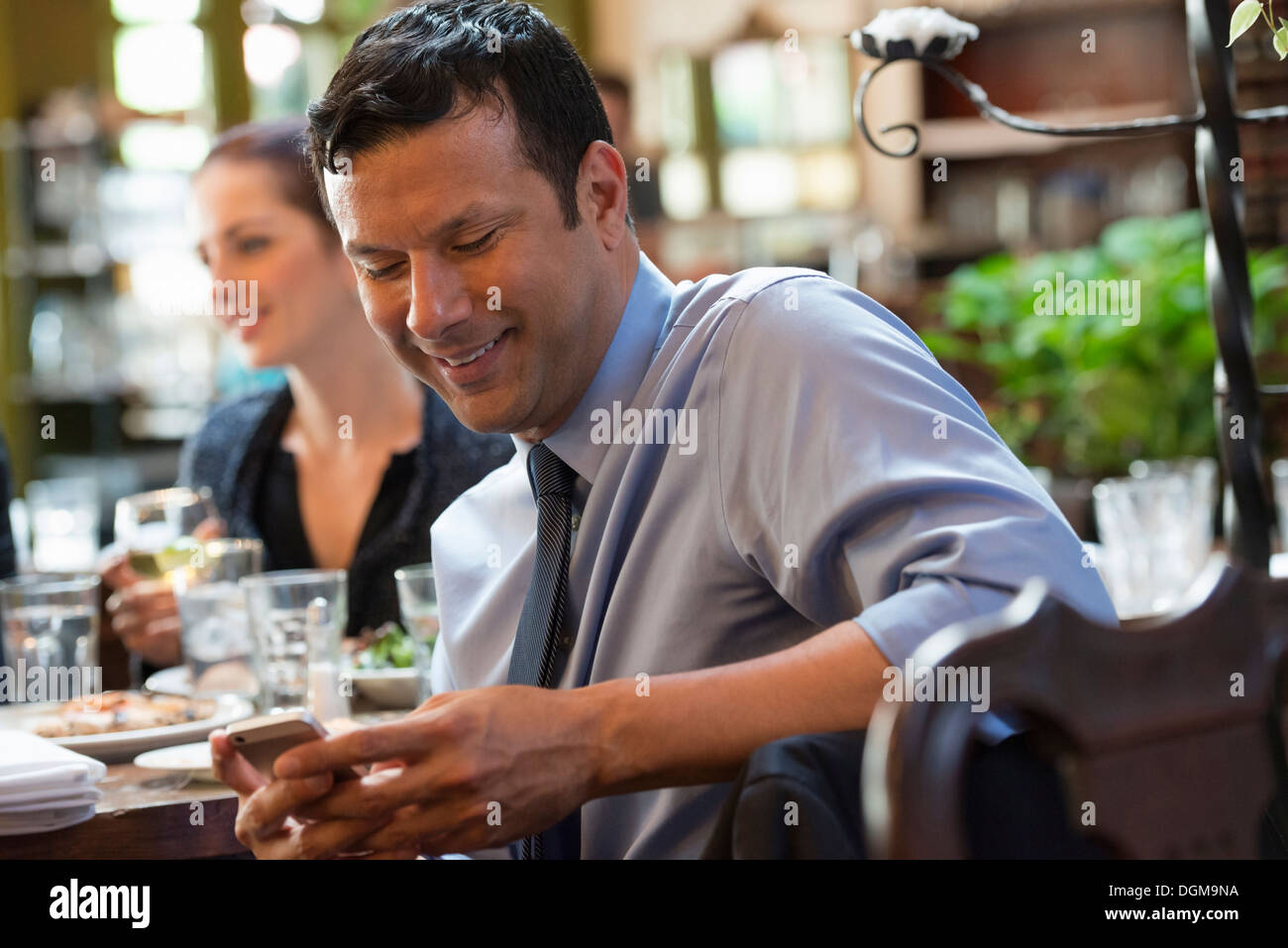 Business-Leute. Drei Menschen an einem Cafétisch, von denen ihr Telefon überprüft wird. Stockfoto