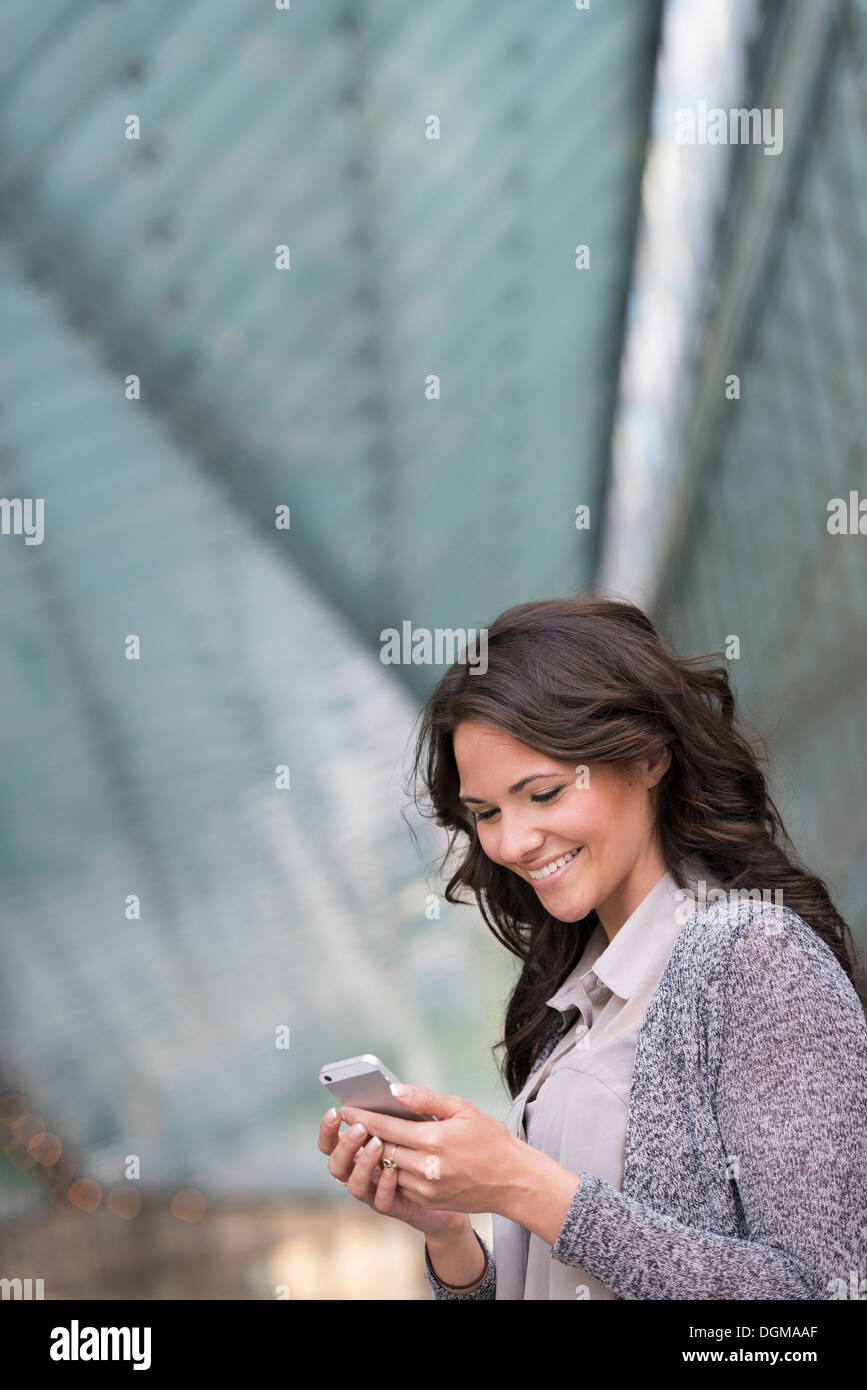 Business-Leute. Eine Geschäftsfrau in eine leichte graue Jacke mit ihrem Smartphone. Stockfoto