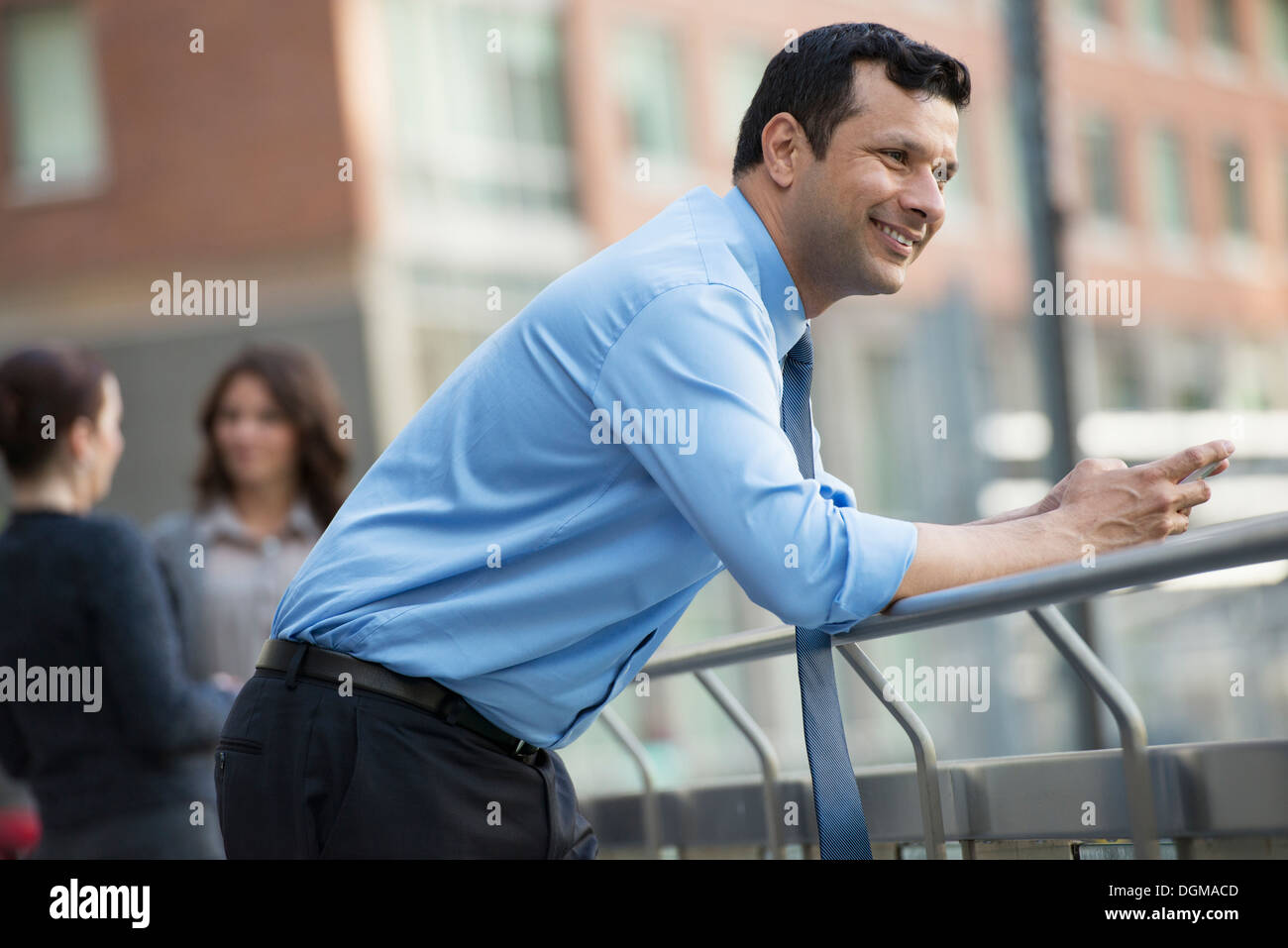 Geschäftsleute im Freien. Ein Latino Geschäftsmann in Hemd und Krawatte, stützte sich auf ein Geländer. Entspannen. Stockfoto