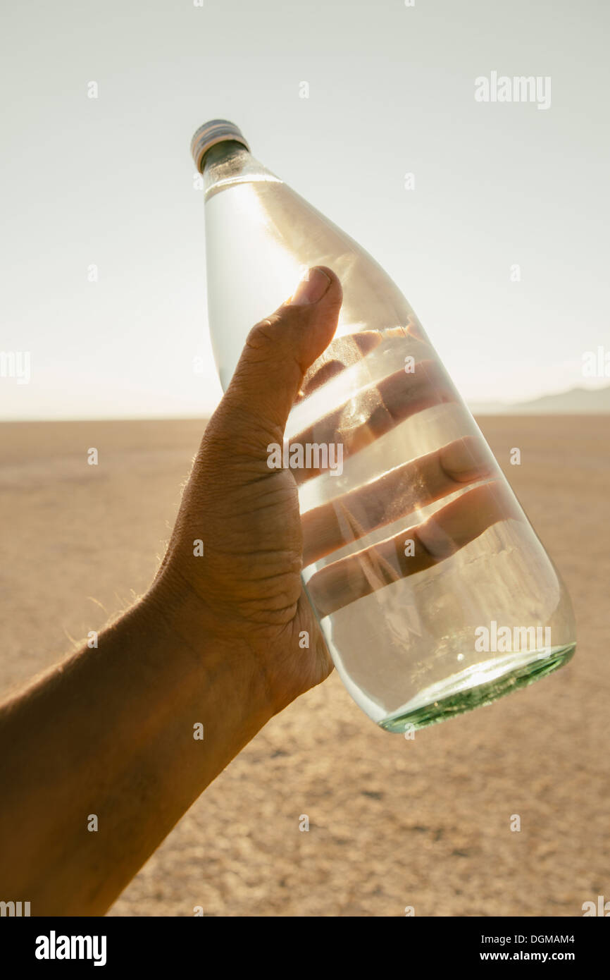 Die Landschaft der Black Rock Desert in Nevada. Die Hand eines Mannes mit einer Flasche Wasser. Gefilterte Mineralwasser. Stockfoto
