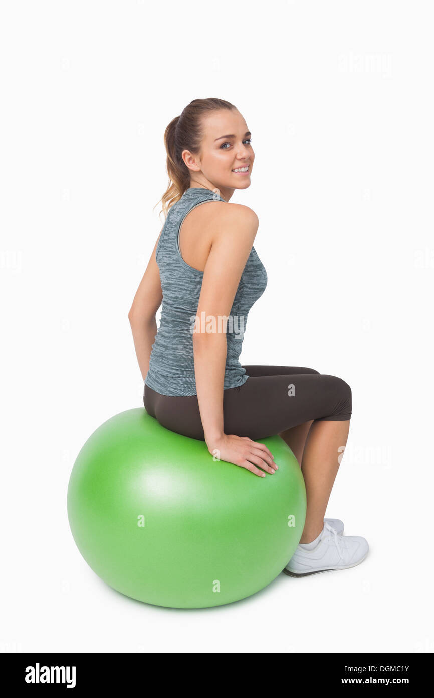 Junge Frau sitzt auf Fitness-Ball über die Schulter in die Kamera schaut Stockfoto