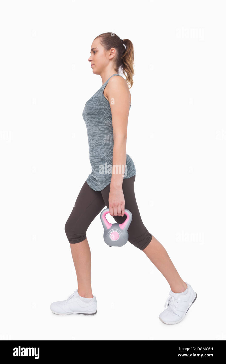 Sportliche Frau trainieren ihren Körper zu Fuß mit einem Wasserkocher Glocke Stockfoto