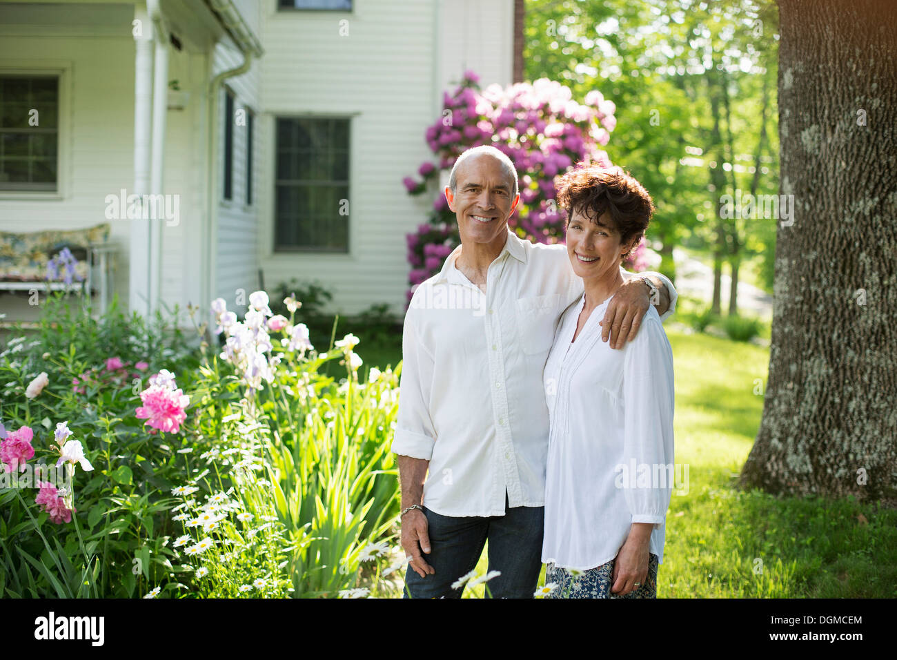 Bio-Bauernhof. Sommer-Party. Ein älteres Paar in weißen Hemden, die unter den Blumen zusammenstehen. Stockfoto