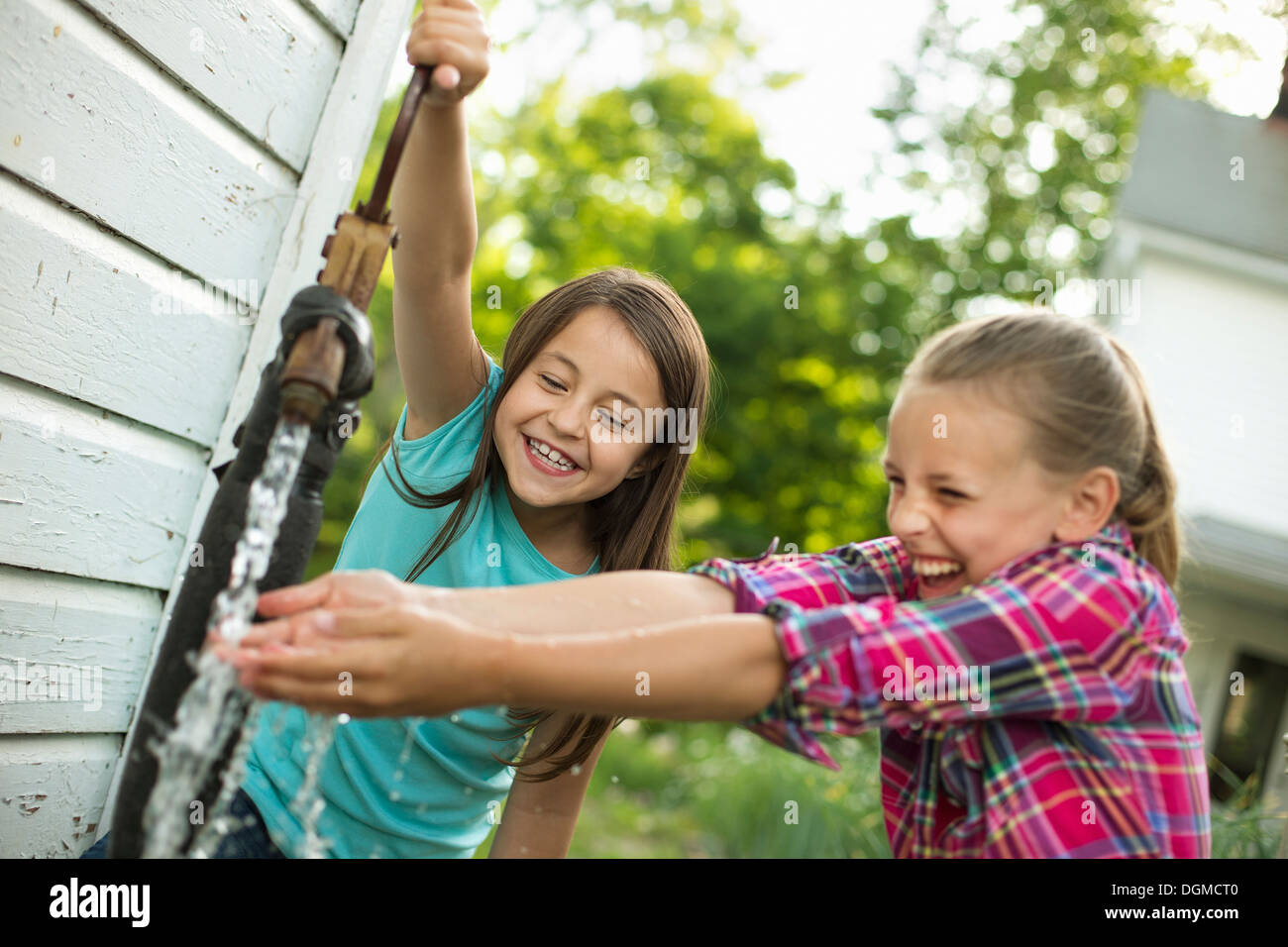 Bio-Bauernhof. Zwei Mädchen waschen ihre Hände unter die Strömung von Wasser von einer Pumpe im Hof. Stockfoto