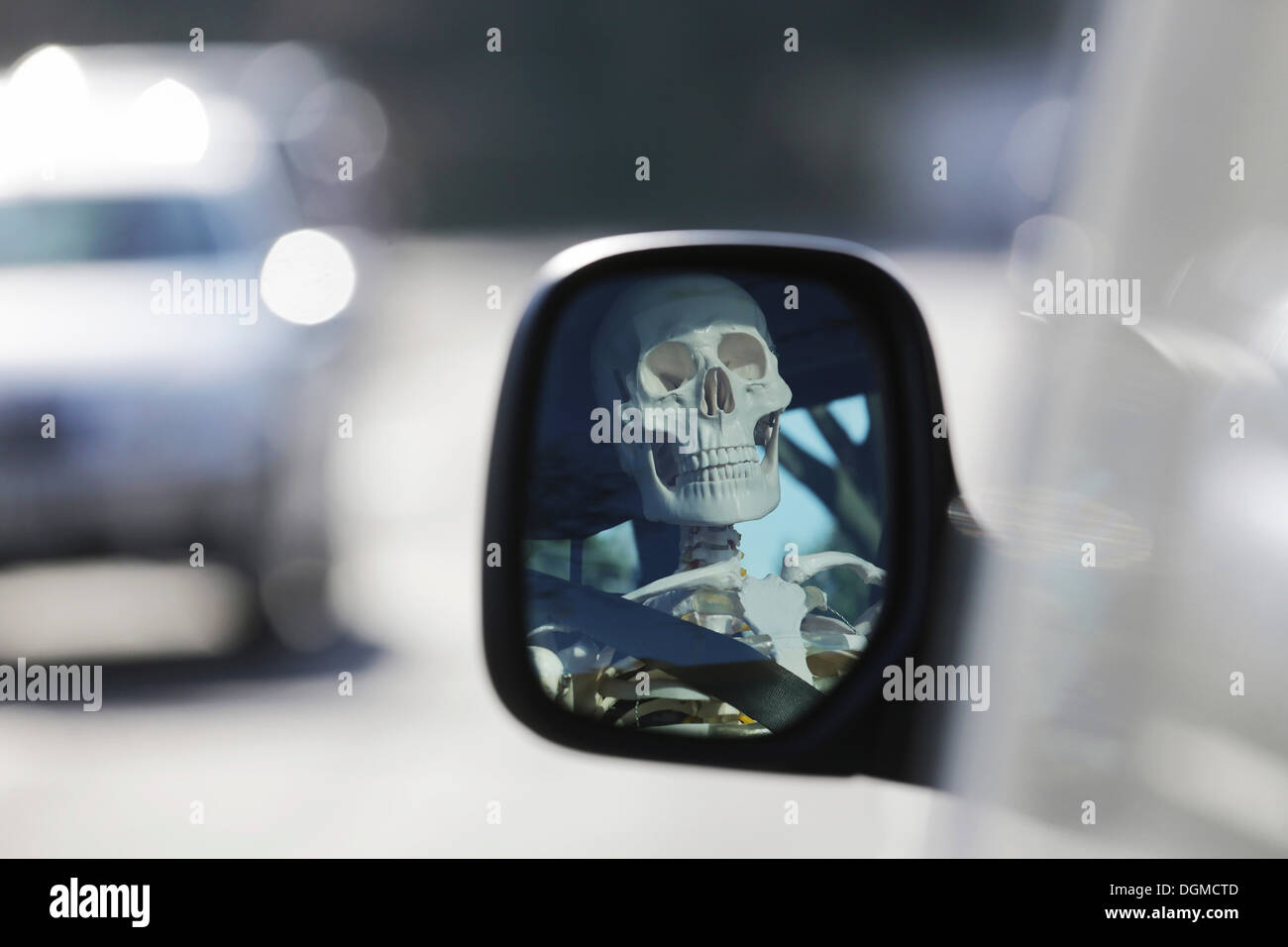 Skelett am Steuer eines Autos, reflektiert Schädel in den Außenspiegel eines Autos, Deutschland Stockfoto