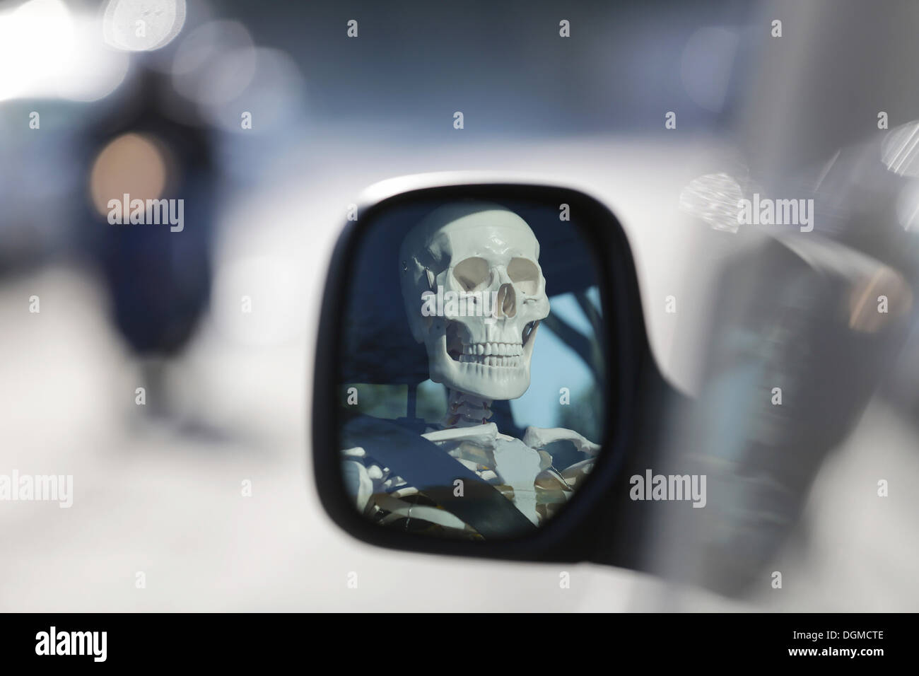 Skelett am Steuer eines Autos, reflektiert Schädel in den Außenspiegel eines Autos, Deutschland Stockfoto