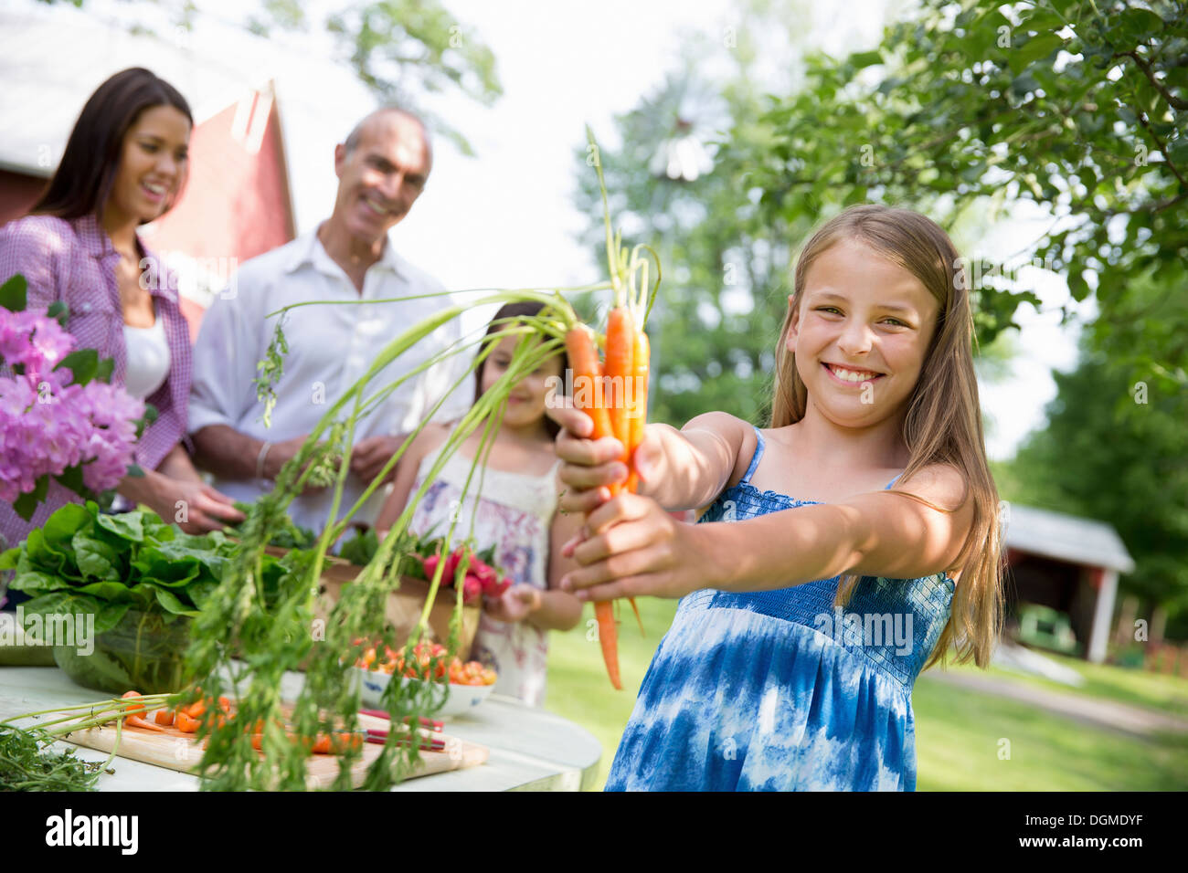 Familienfest. Ein Tisch gedeckt mit Salaten und frischem Obst und Gemüse Kind hält sich frisch gepflückten Karotten. Stockfoto