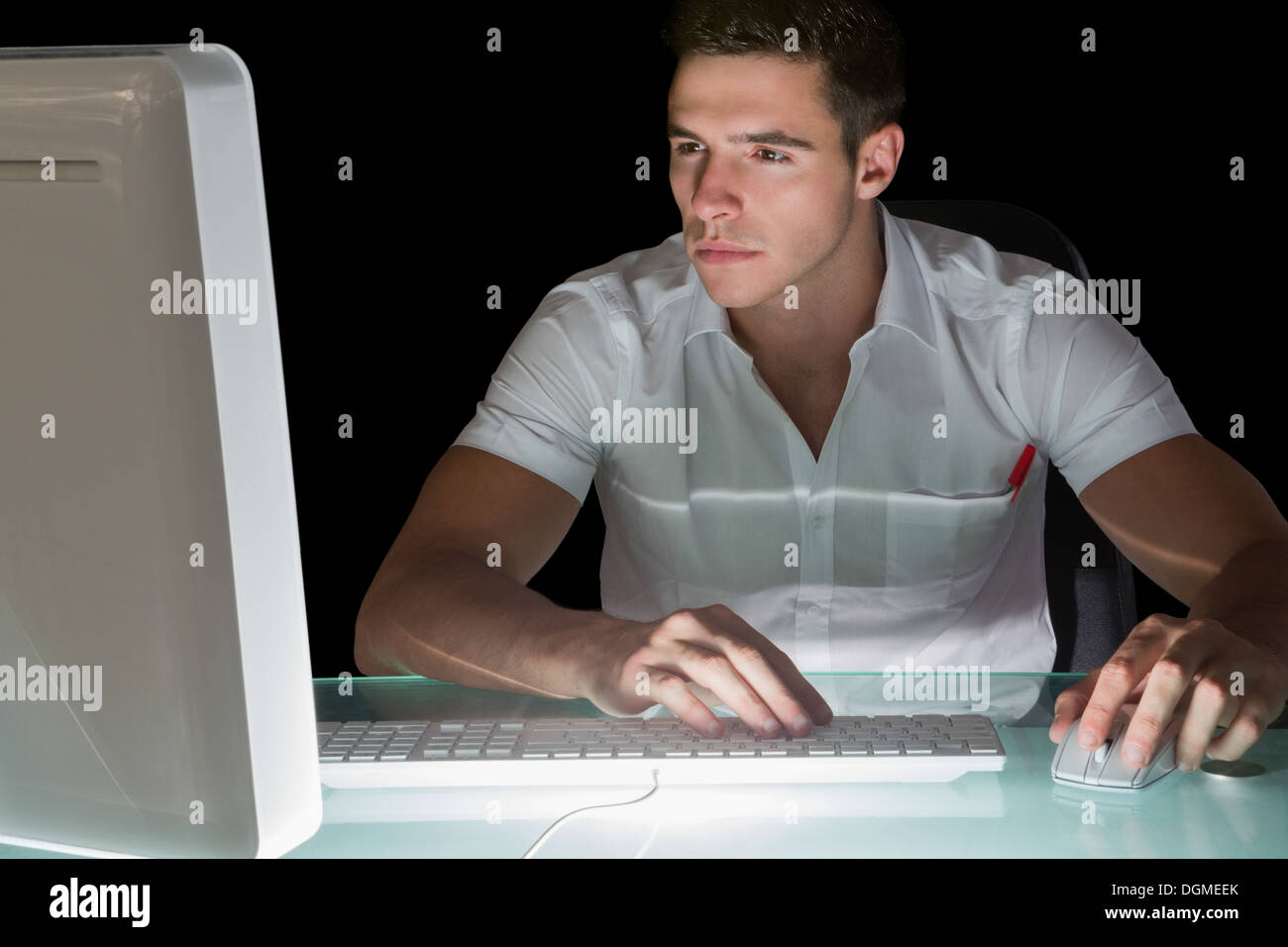 Gut aussehend fokussierte Computeringenieur arbeitet in der Nacht Stockfoto