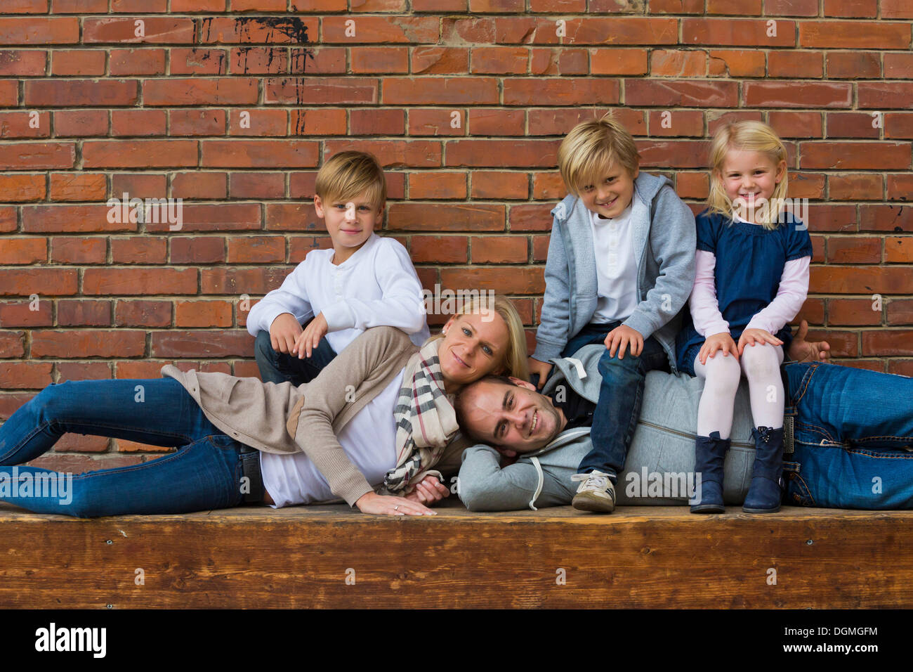 Familienbild mit drei Kindern, die Eltern liegen, die Kinder sitzen auf Ihnen Stockfoto