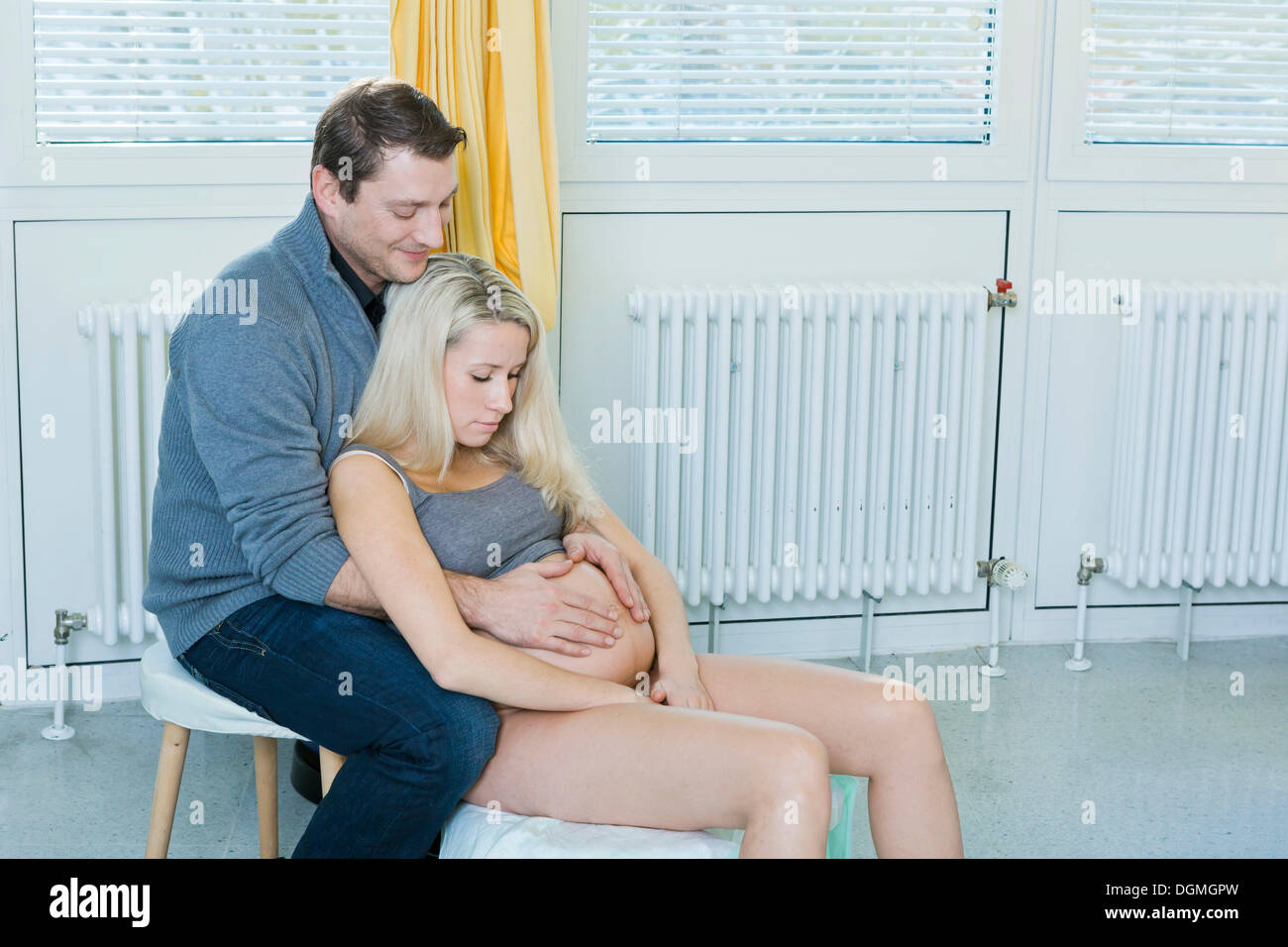Mann und Frau im Kreißsaal während der Geburt, die Frau sitzt auf einem Hocker Geburt während der Entbindung, Deutschland Stockfoto