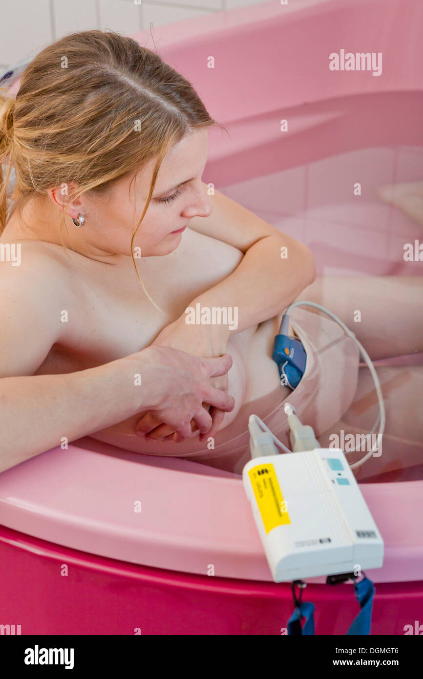 Frau während der Geburt mit einem Kardiotokografie oder CTG in einem Geburt Bad in der Mutterschaft Kreißsaal, Deutschland Stockfoto